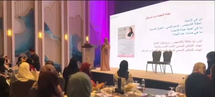 جلسة على المنصة، وعلى الشاشة: «عيادة الناجيات من السرطان» (من تغطية الإخبارية).